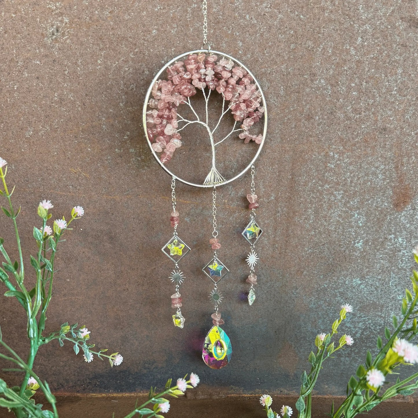 Decorative Decorative Tree of Life Crystal Sun Catcher - Strawberry Quartz hanging ornament with tree design and colorful beads against a textured brown background