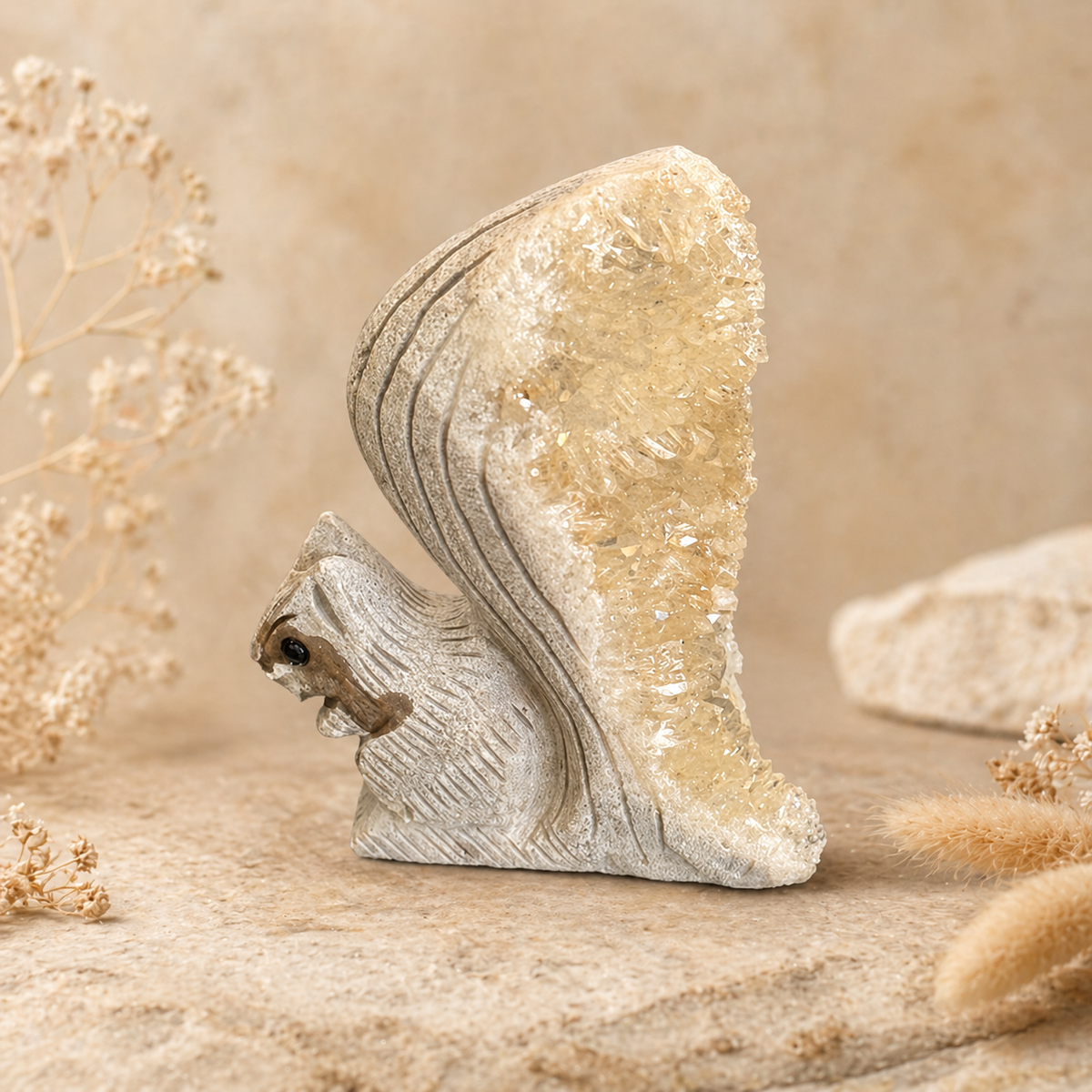 White squirrel geode crystal carving with cream druzy crystal cluster tail displayed with dried pampas grass
