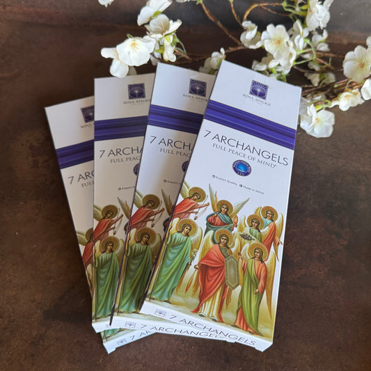 Packets of '7 Archangels' incense with angel illustrations on a wooden surface.