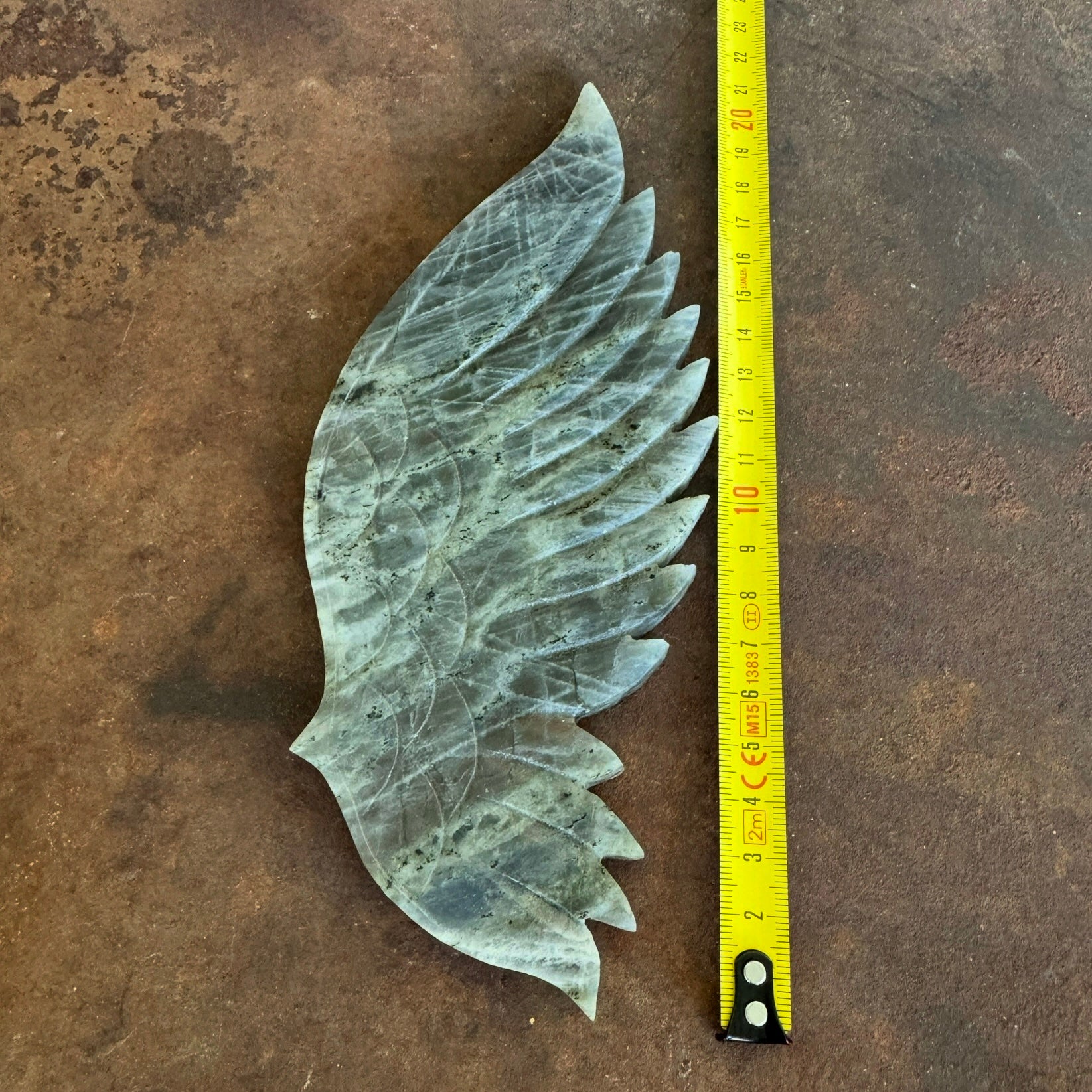 Extra Large Purple Labradorite Crystal Wing next to a measuring tape on a textured surface