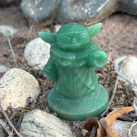 Green Aventurine Baby Yoda crystal carving photographed among natural stones