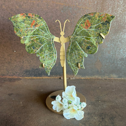 Butterfly-shaped stand with green patterned wings and gold body on a brown background