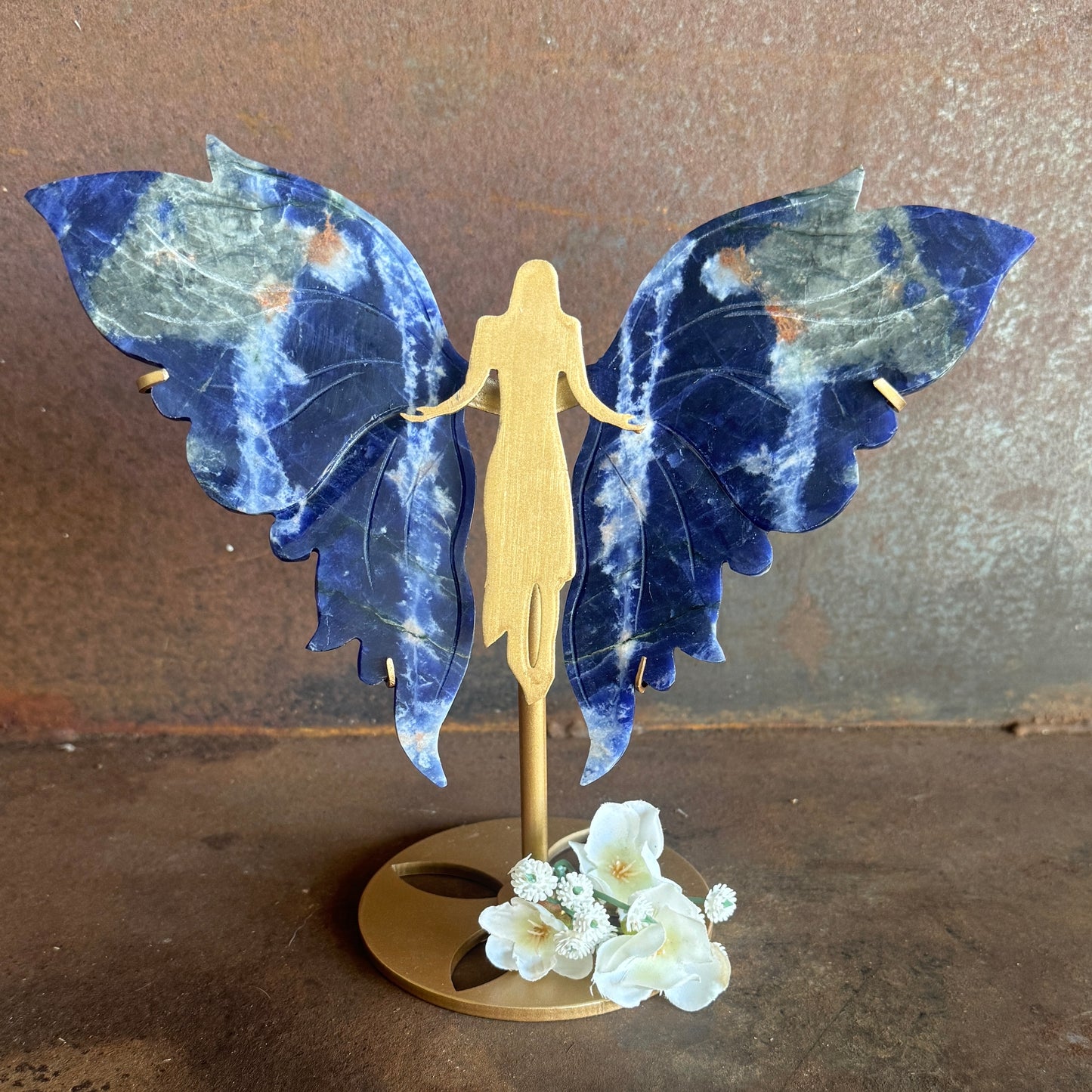 Decorative figure with blue angel wings and a gold body on a brown background