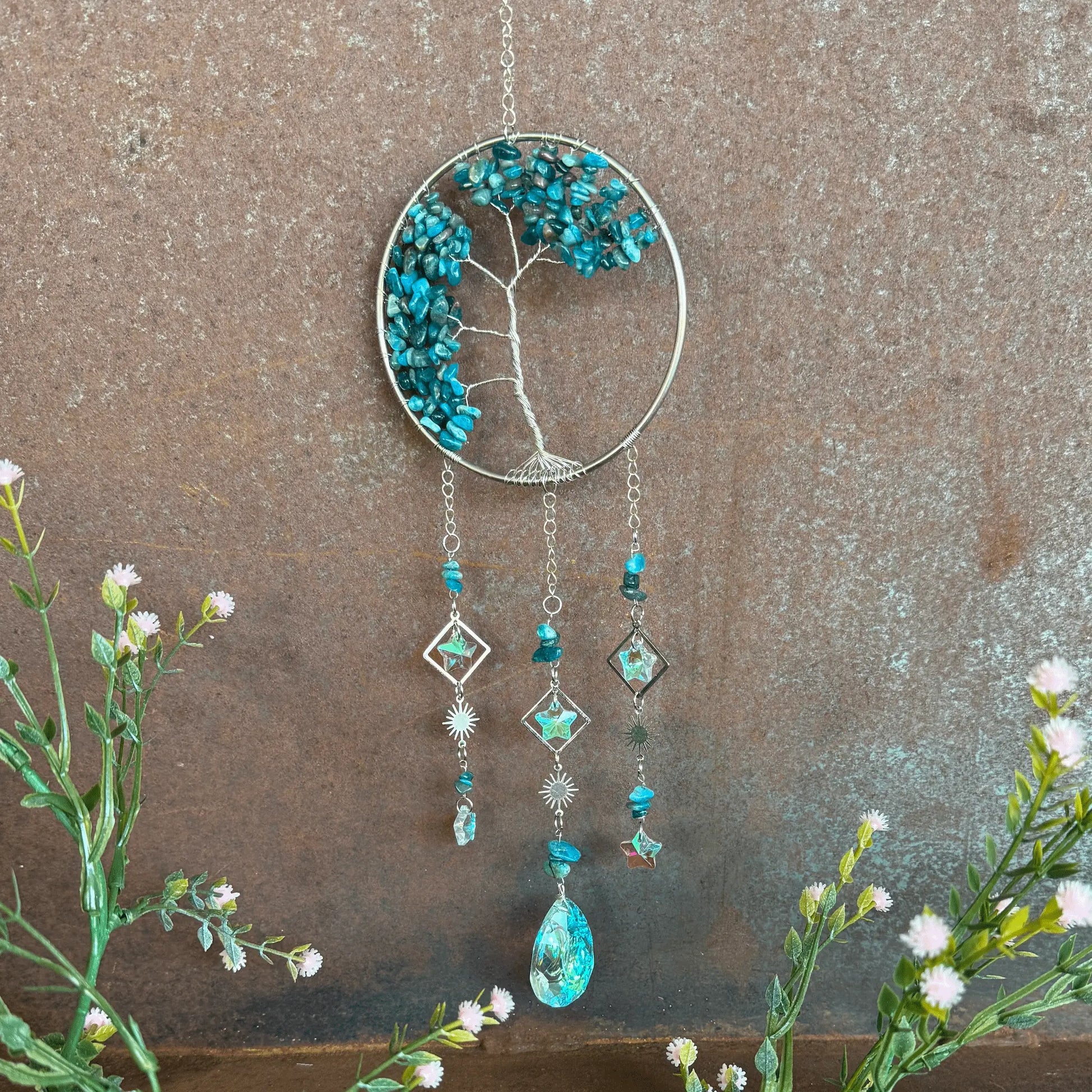 Decorative Tree of Life Crystal Sun Catcher - Apatite hanging ornament with tree design and blue stones on a textured surface.