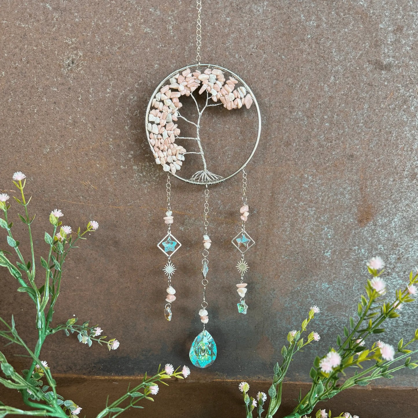 Decorative Tree of Life Crystal Sun Catcher - Pink Opal hanging ornament with floral elements and beads on a textured wall background