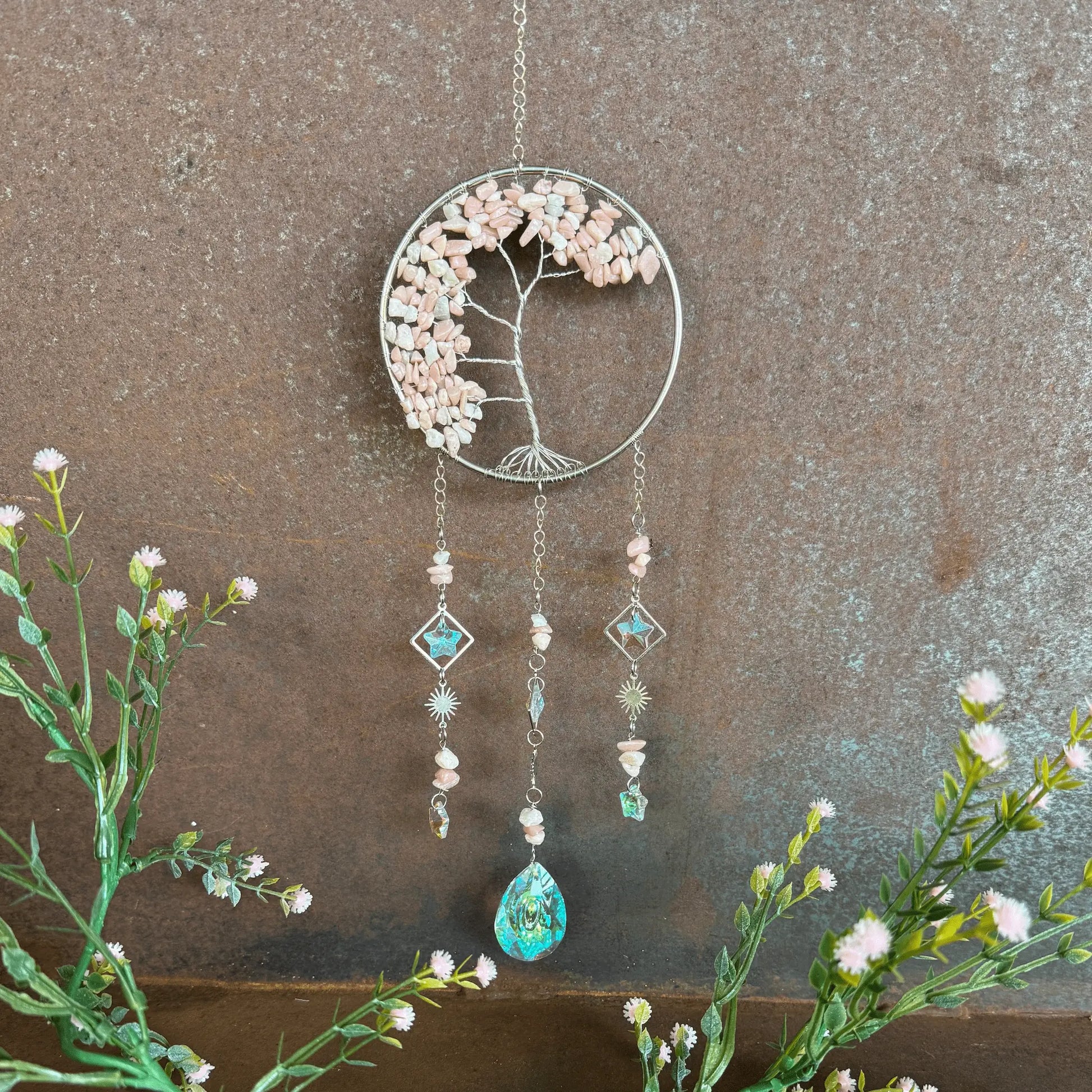 Decorative Tree of Life Crystal Sun Catcher - Pink Opal hanging ornament with floral elements and beads on a textured wall background