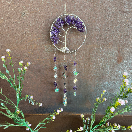 Decorative Tree of Life Crystal Sun Catcher Amethyst hanging crystal tree with purple and stones on a textured wall background.